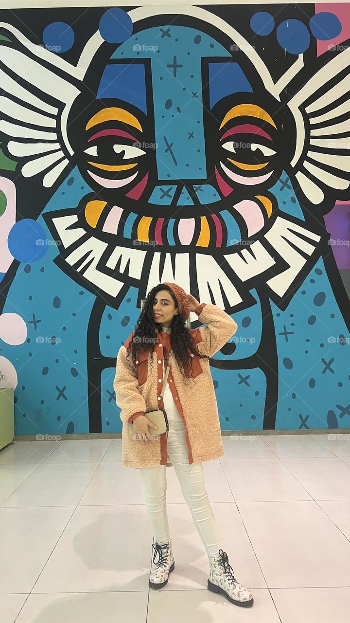 Curly haired girl with winter style and painted wall