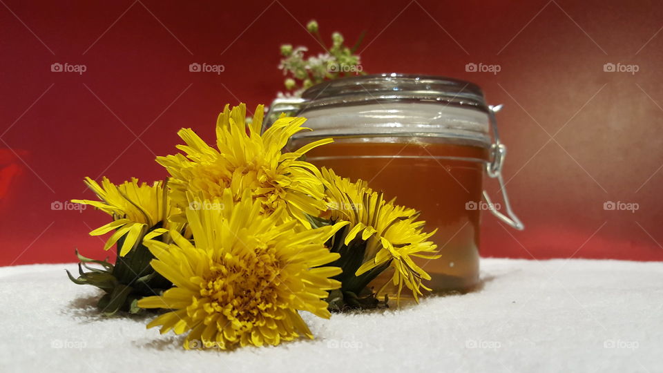 Honey in a jar and fresh yellow flowers