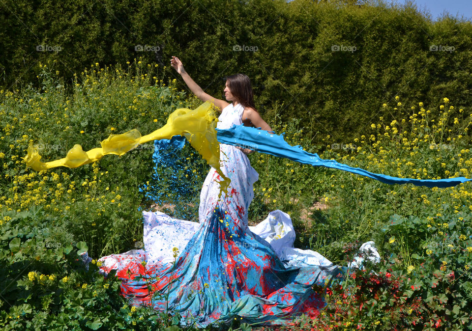 Blue and yellow color paint splashing on young woman