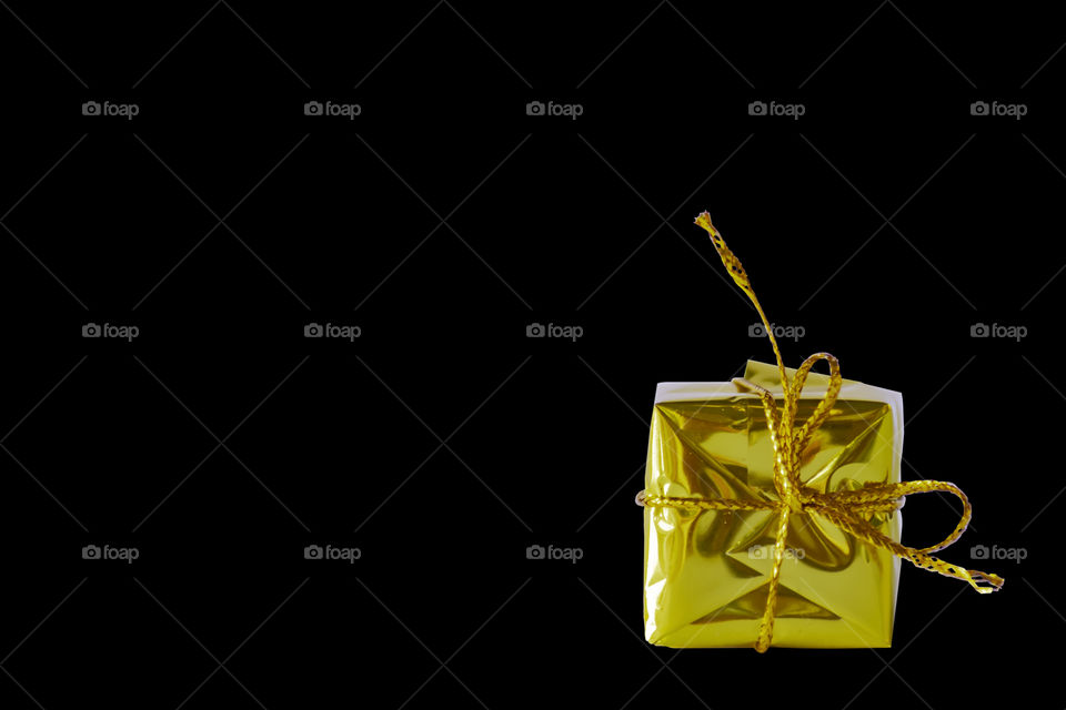 Isolated Gift box gold for the festivities on a black background with clipping path.