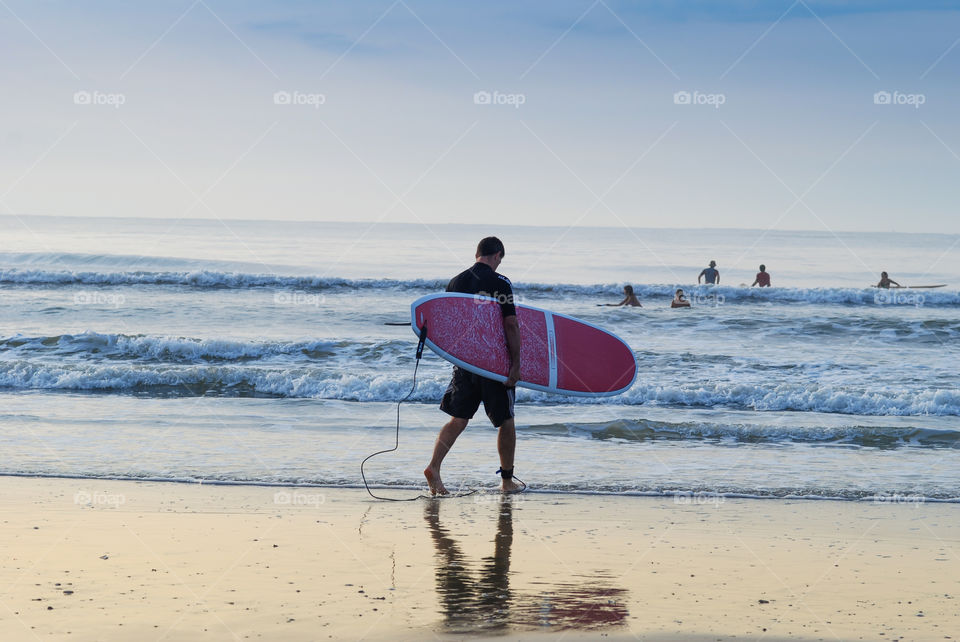 Young Male Surfer on the Beach with His Surf Board