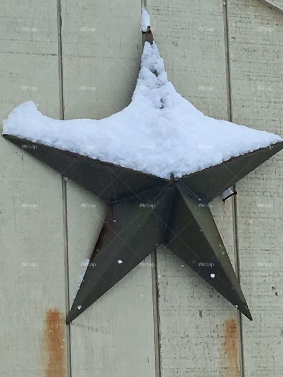 Snow covered star on side of building 
