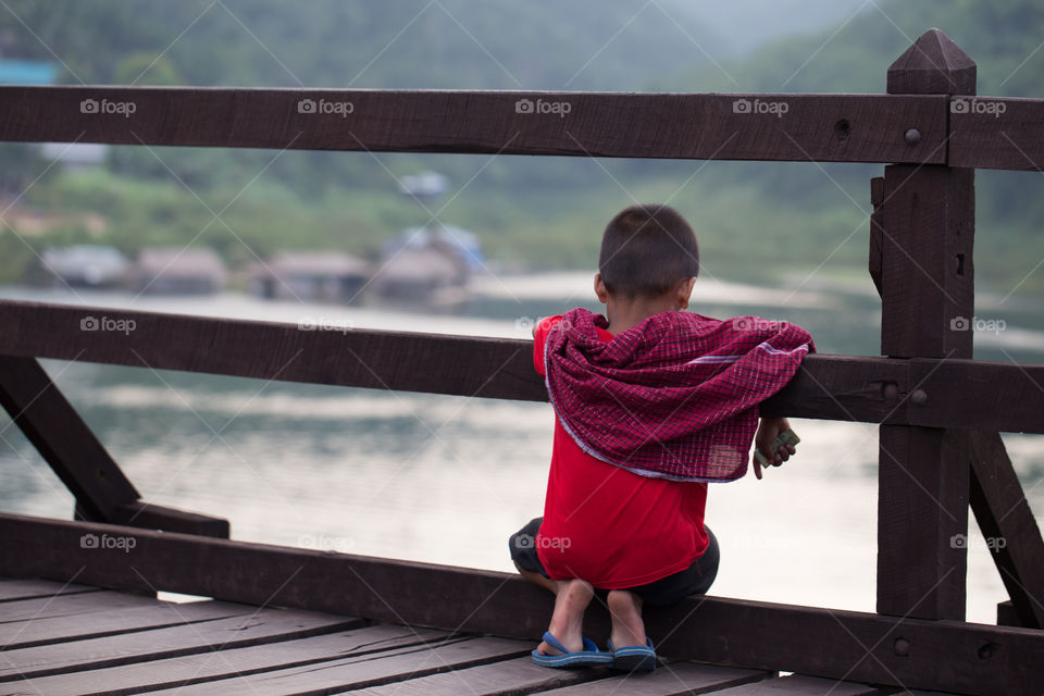 Boy looking to the river on the bridge