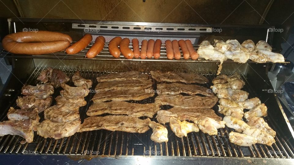starting up the grill. hot dogs, sausage, beef riblets and chicken