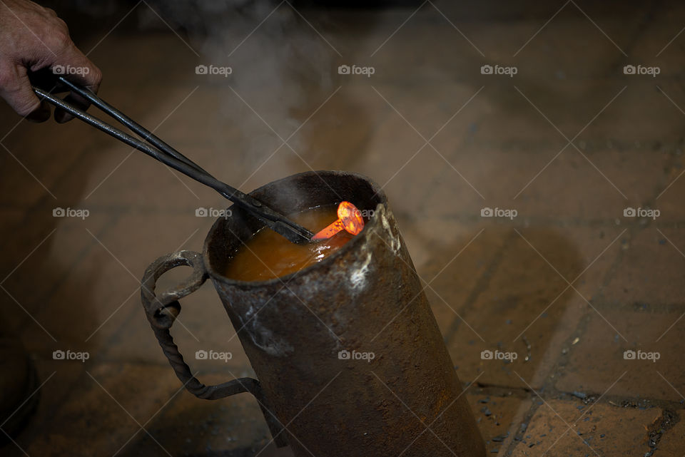 blacksmith puts a hot metal nail in cold water