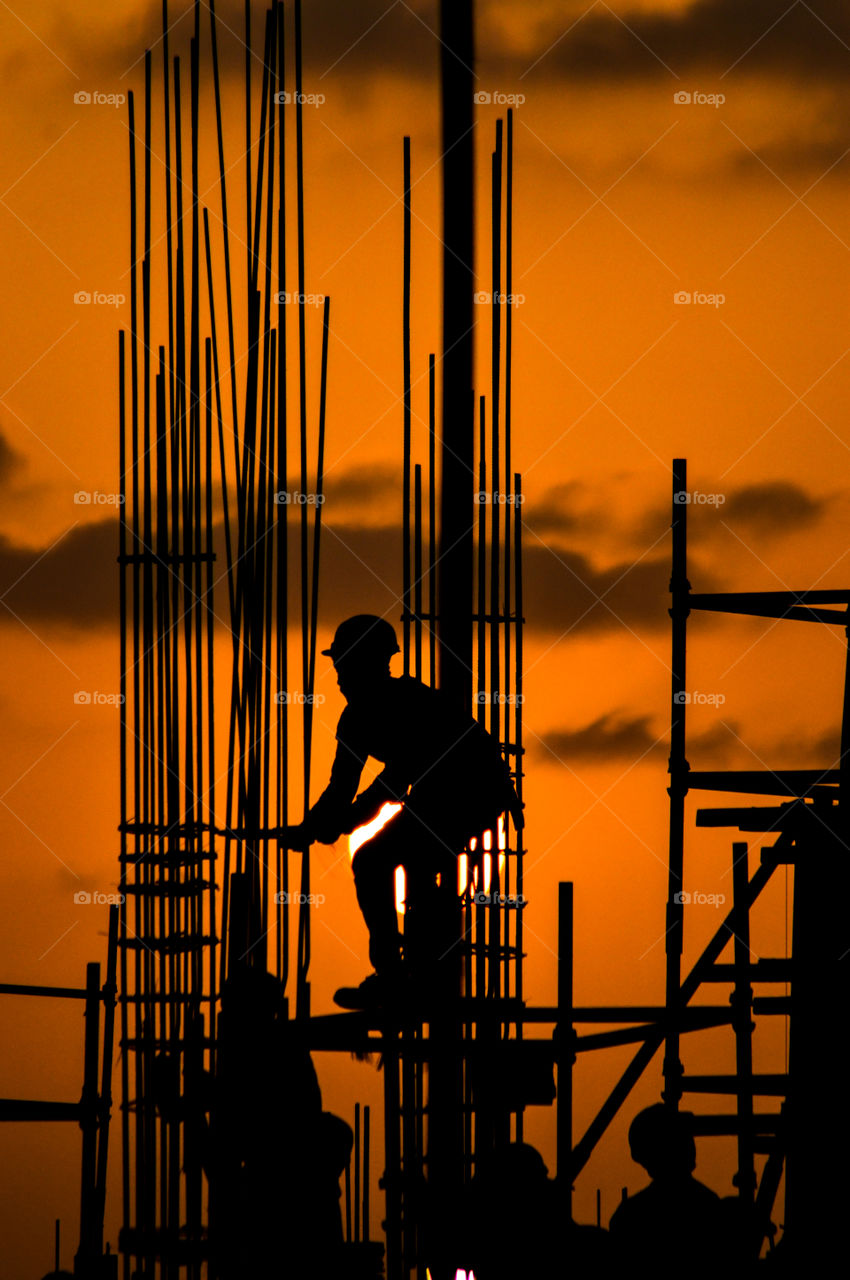 Silhouette of a man working on a construction site