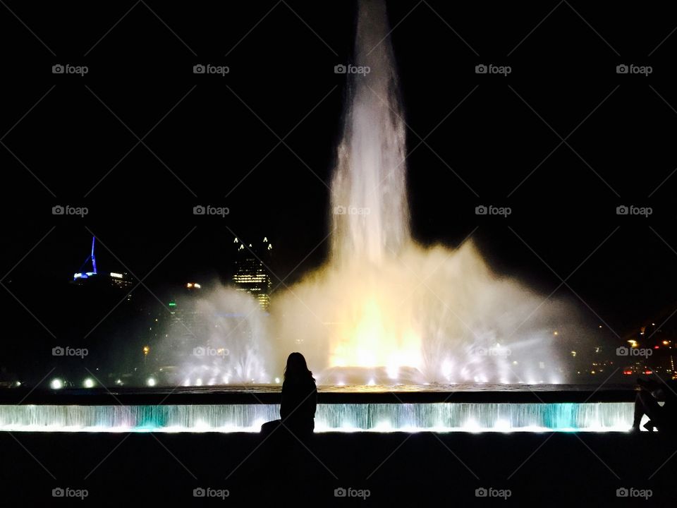 Girl looks longingly into fountain lights at Point State Park in Pittsburgh, PA. 