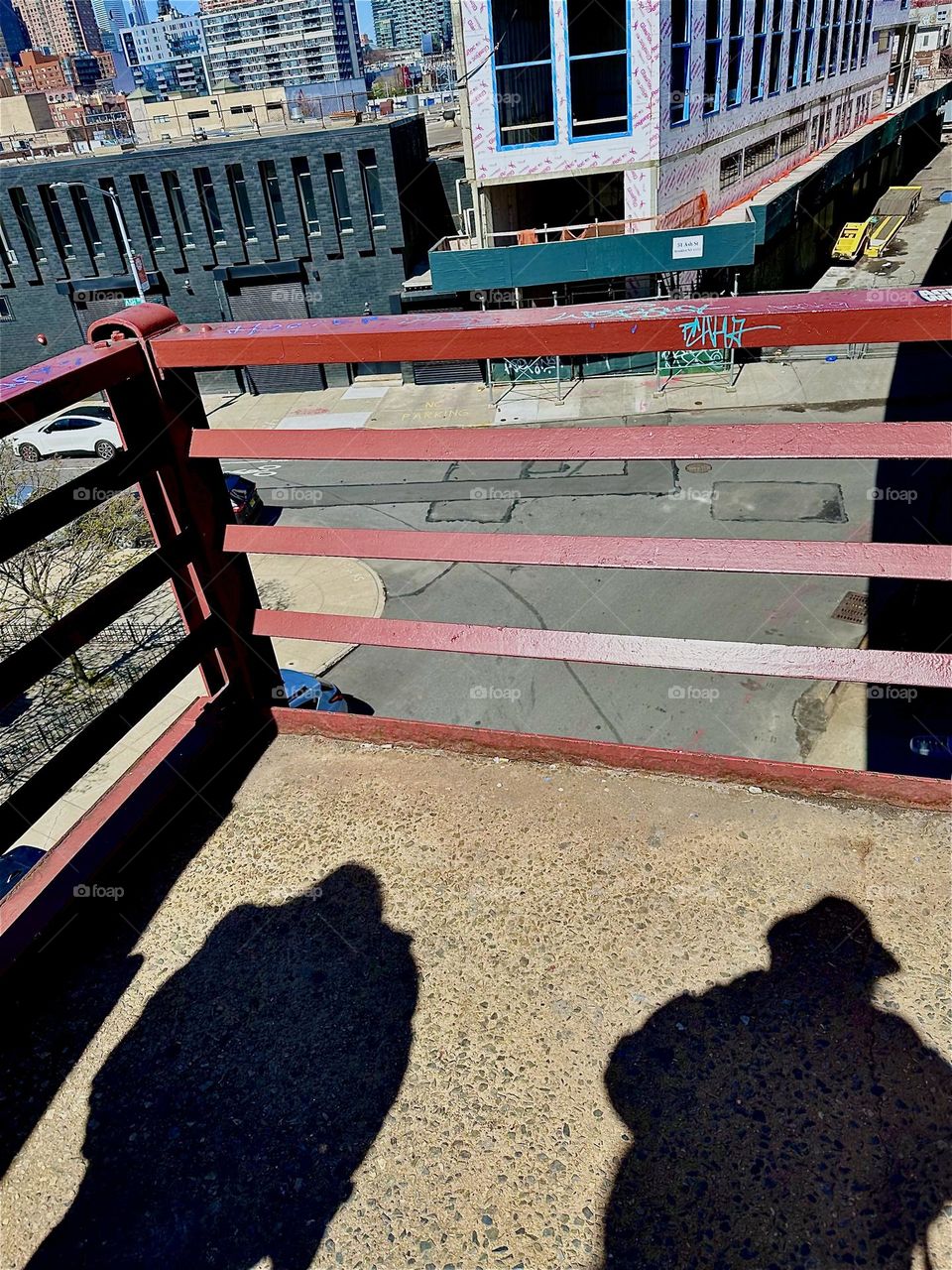 The three story tall red metal staircase of the “Pulaski Bridge” at “Newtown Creek” that connects LIC, Queens to “Greenpoint”, Brooklyn often shows these poignant shadows of pedestrians walking by. 2024. Hypnotic Productions