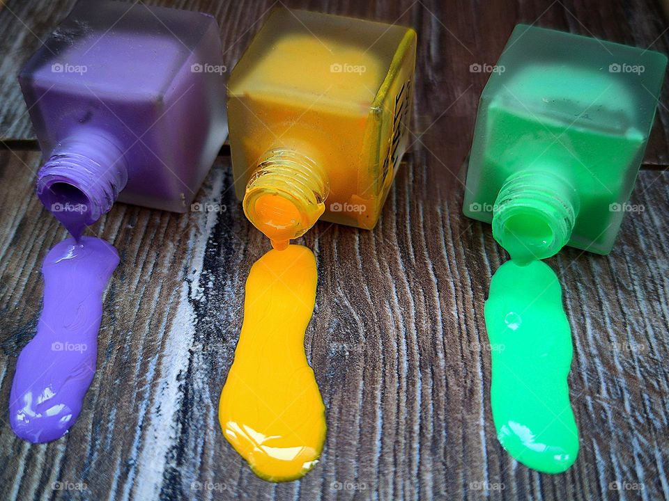 Three vials of flow out nail polish: purple, yellow and green