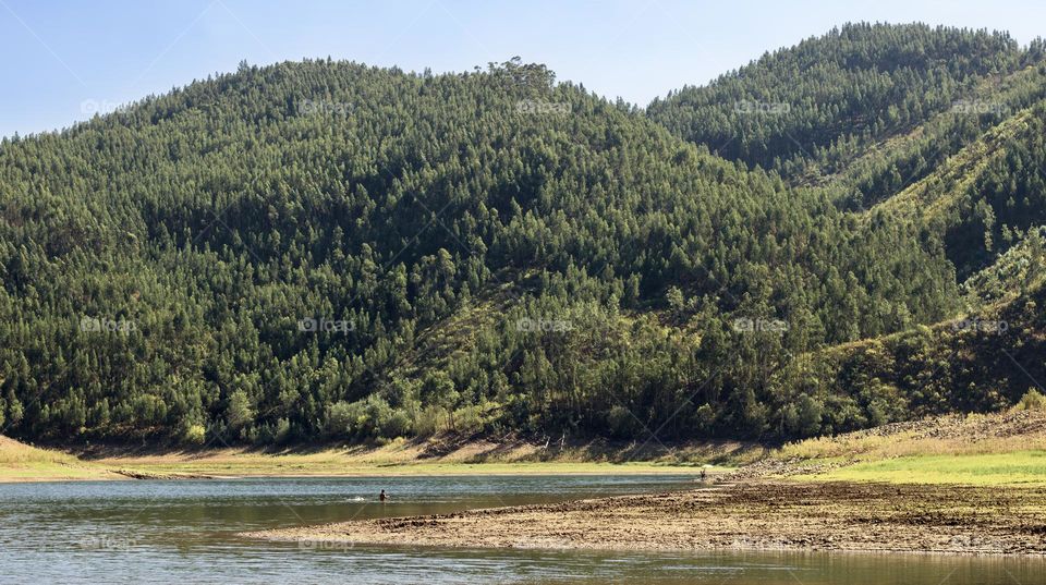 Tree covered mountains provide the backdrop for wild swimming in the river