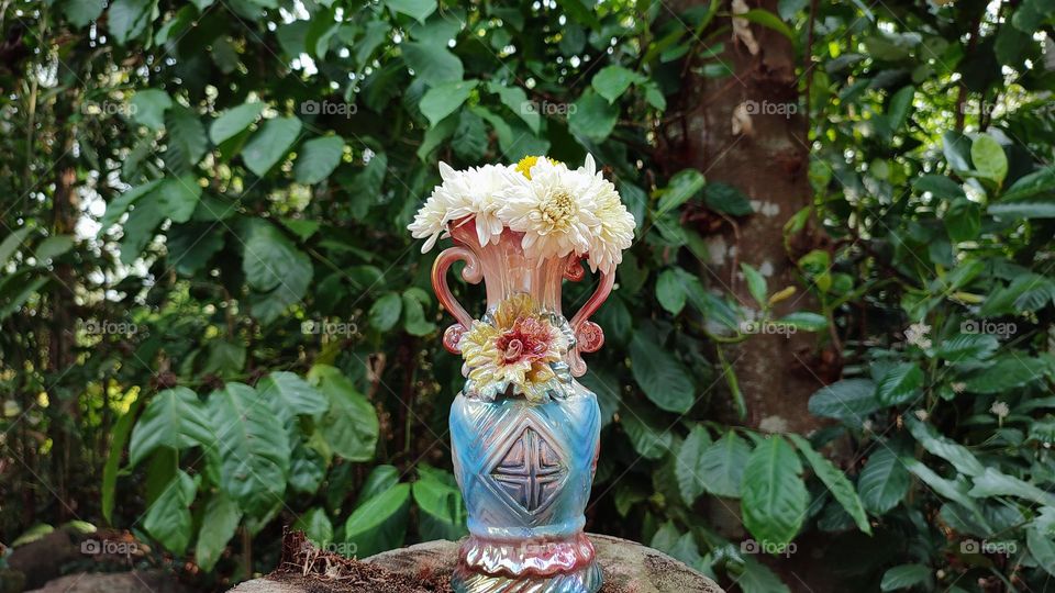 Beautiful white flowers in a colourful flowerpot with a flower sculpture, Flowers in a vase, colourful vase, white flowers in a vase