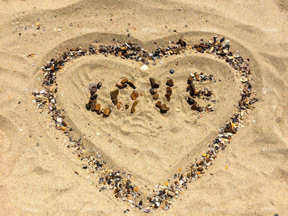 Love letter with stones and shells on a sand