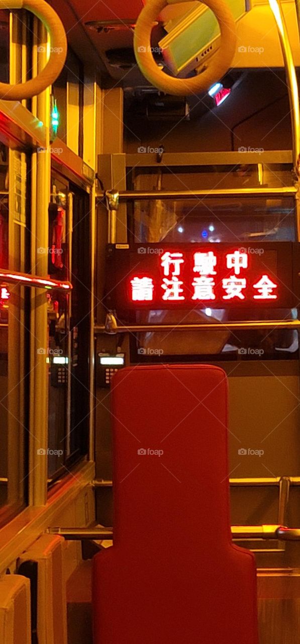 A retro-style bus with a warm yellow light interior. The marquee reads "Please pay attention to safety while driving" in Chinese