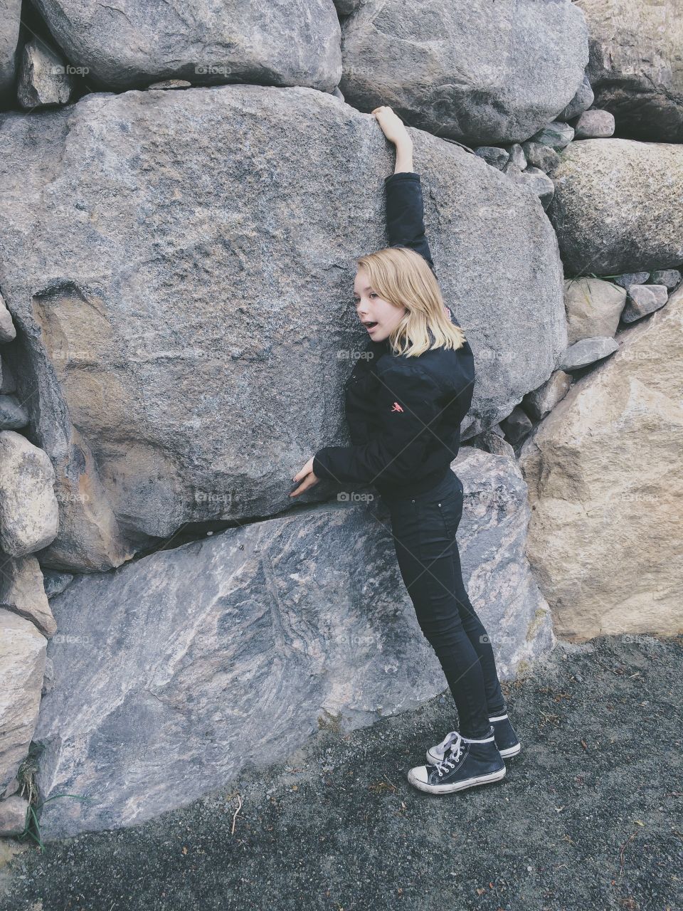 Climbs stonewall. A girl trying to climb the stonewall