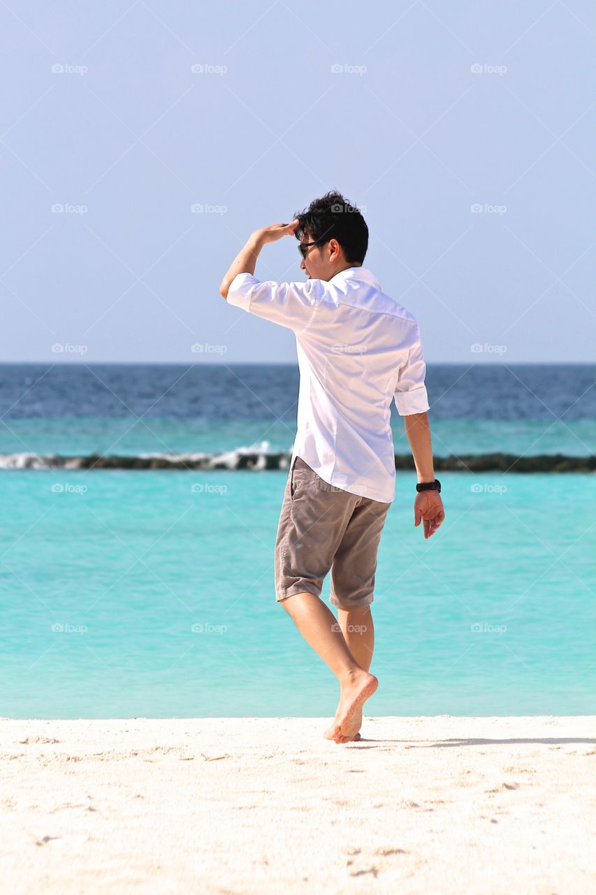 Sunny. A man walking on the sunny beach