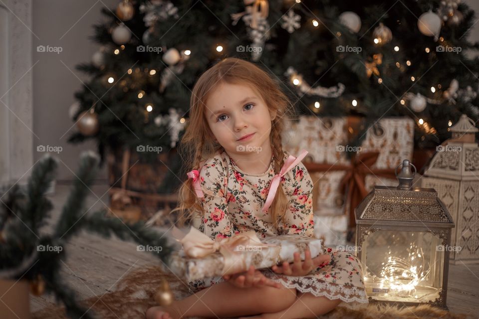 Little girl near Christmas tree at home