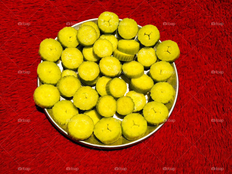 Fresh cucumber slices in steel plate on red background