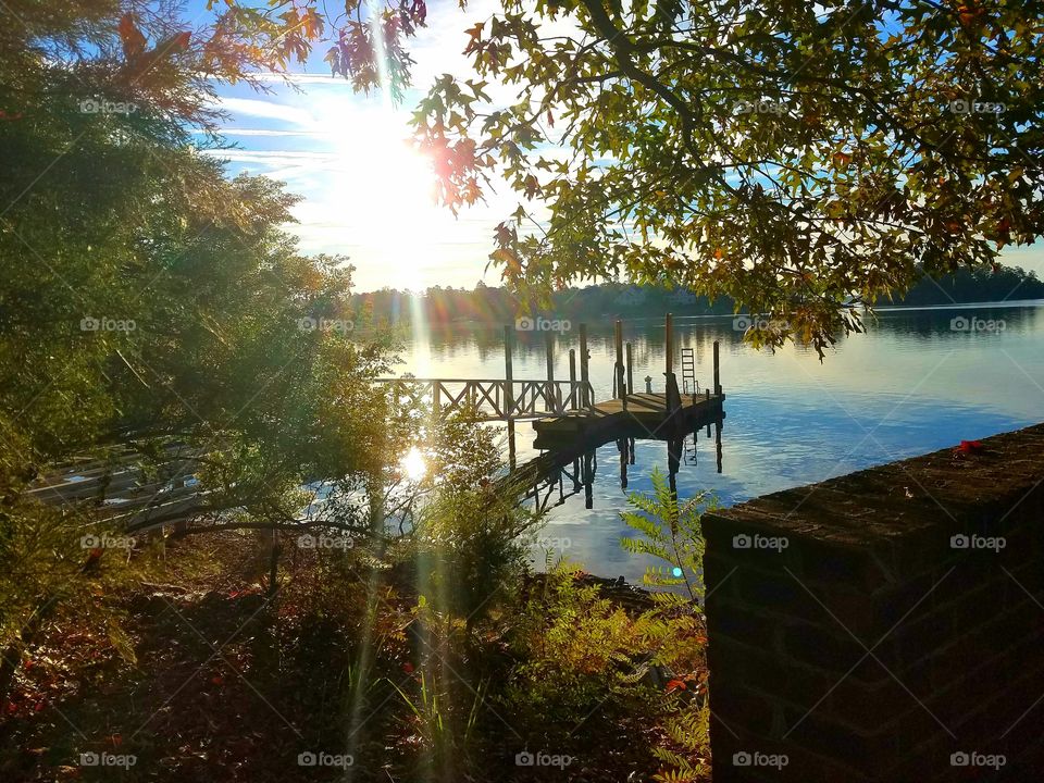 sun reflecting on water by a dock