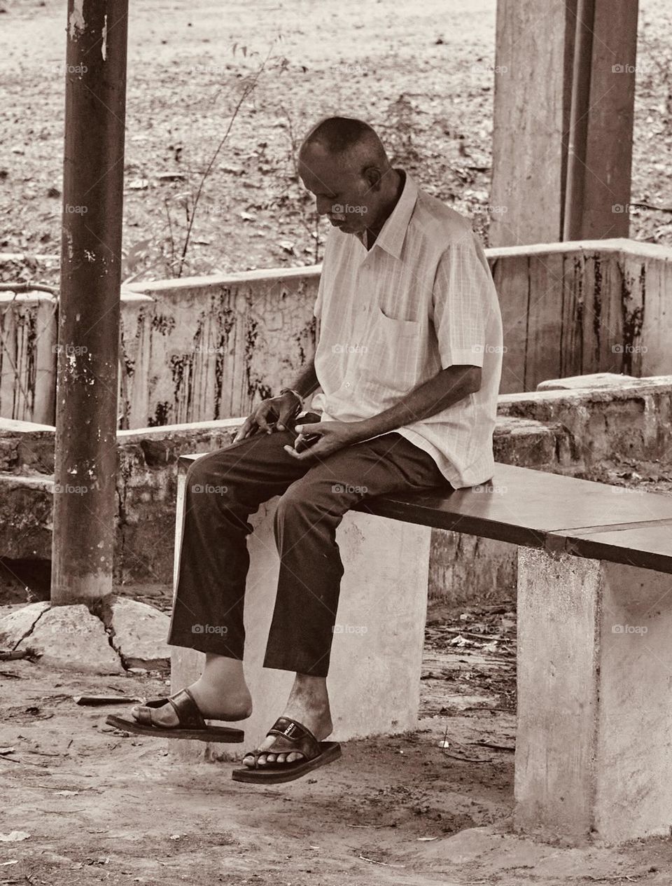 An old father sitting alone in a stone bench 