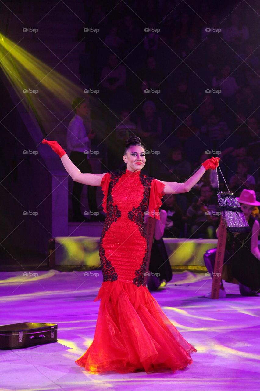 girl actress on stage in a red dress performs steps