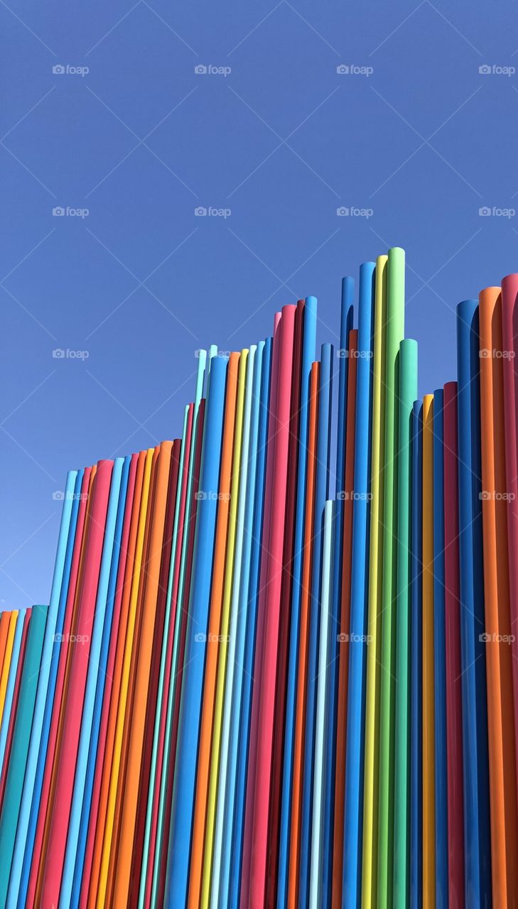 Artist architecture installation with rainbow colors set against a cloudless blue sky