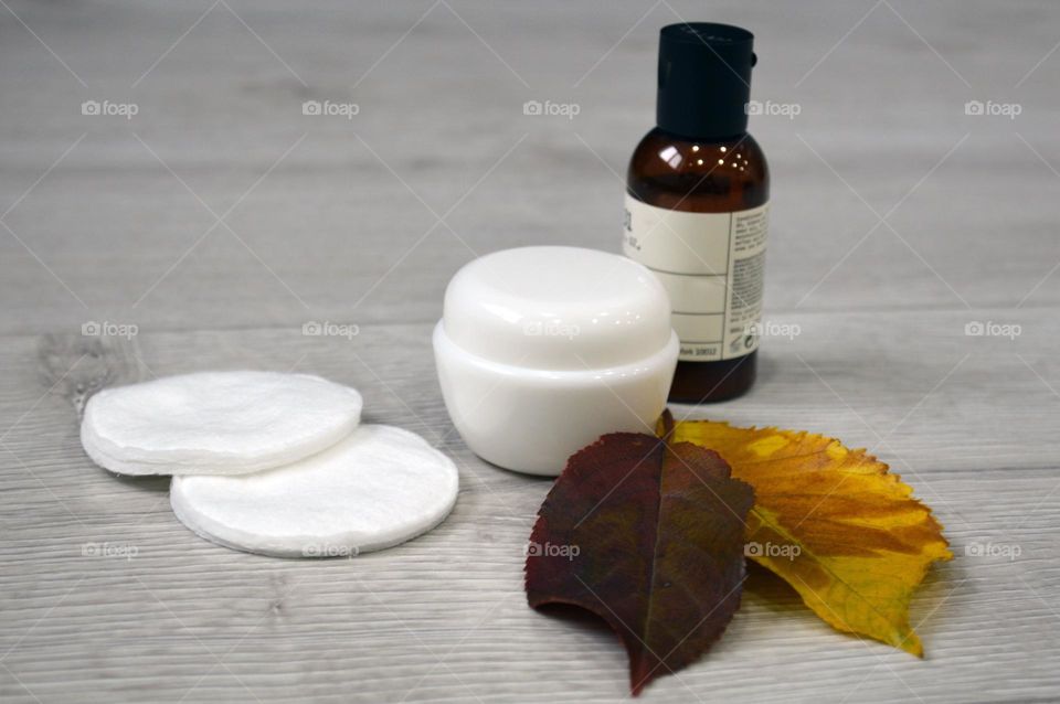 Jars with cream, shampoo and cosmetics on a background with autumn leaves