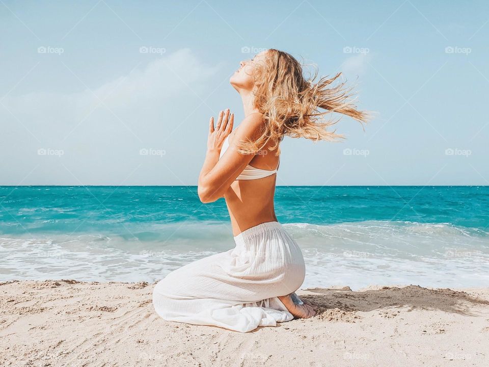 Woman sitting in the beach meditating 