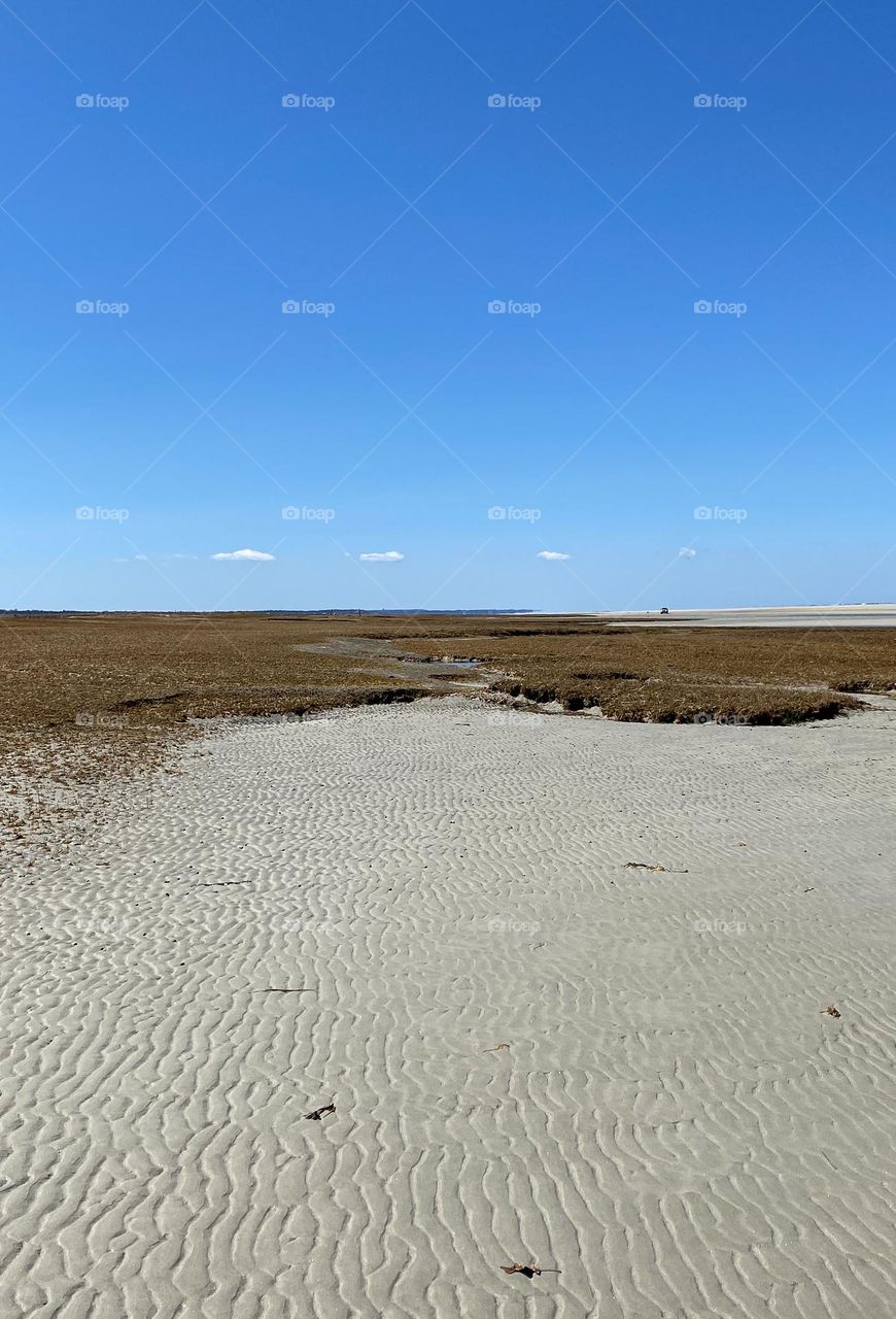 Small clouds in a line on the horizon, low tide goes so far out you can’t even see the ocean.  