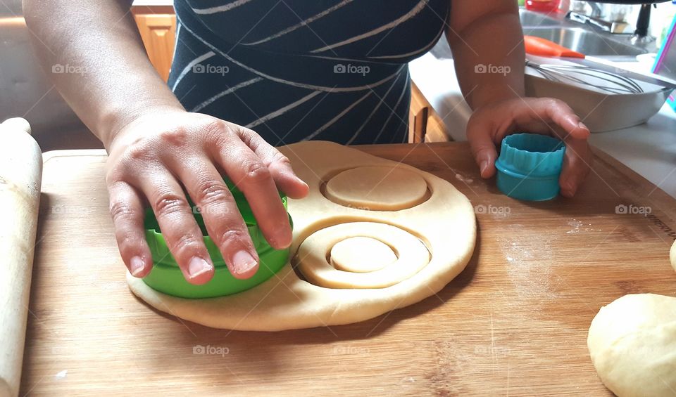 Woman using pastry cutter on donut dough