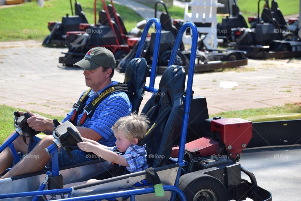 A boy and his dad riding go carts