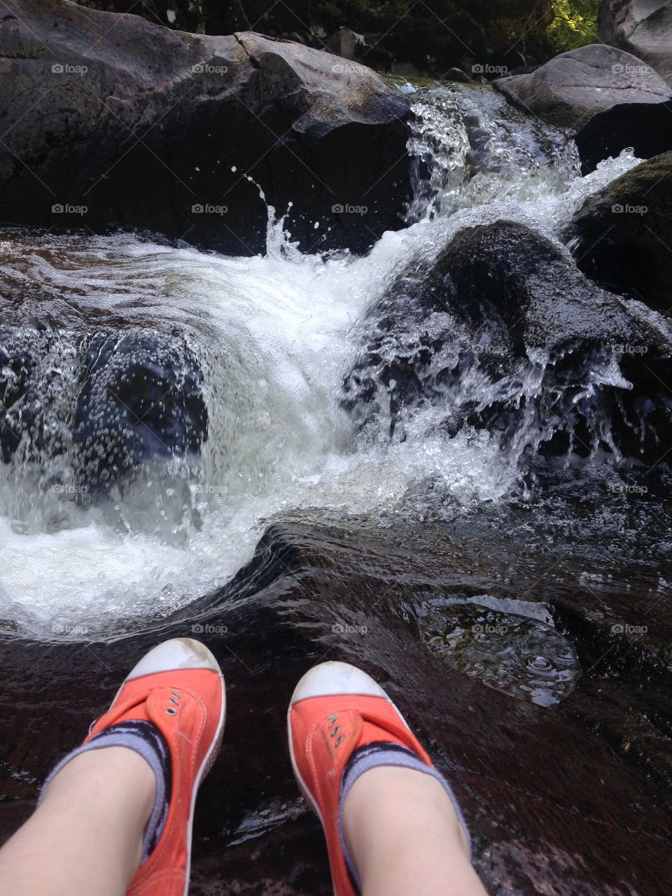 Low section of woman leg on rock by river