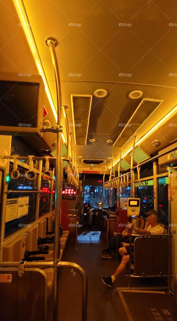 A retro-style bus with a warm yellow light interior.card reader.handrail ring.bus interior.Bus handrail ring.bus seat