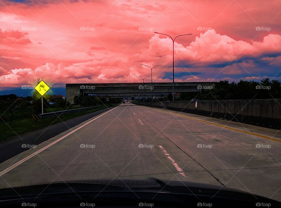 Traffic signs for slippery roads, driving on toll roads, warning for slippery roads, warning signs in yellow, black car images, slippery road symbol with black curve lines, beautiful view toll roads, red da bright clouds, red white sky, natural outdo