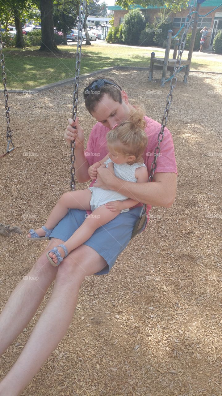 Man enjoying swing with his daughter 
