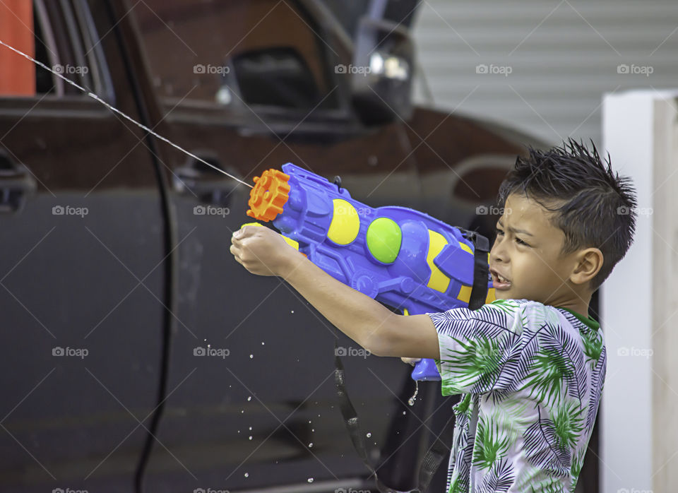 Asian boy holding a water gun play Songkran festival or Thai new year in Thailand.