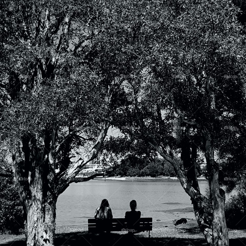 two people sitting at the park bench