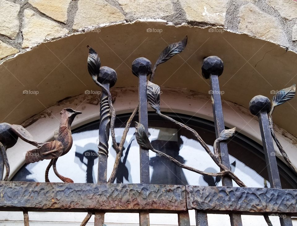 Metal lattice on the window with elements of leaves and birds