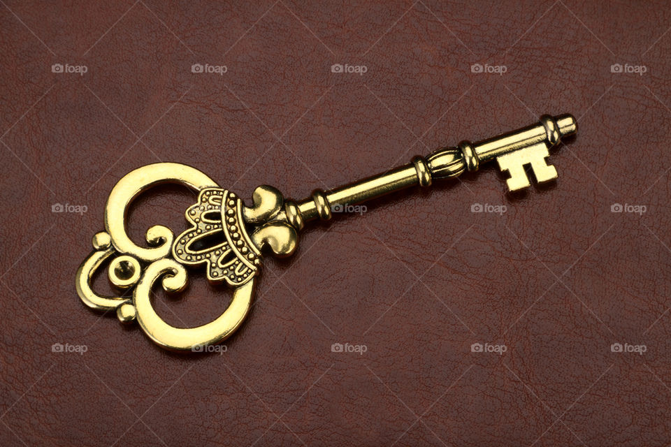 Beautiful antique golden key on brown leather