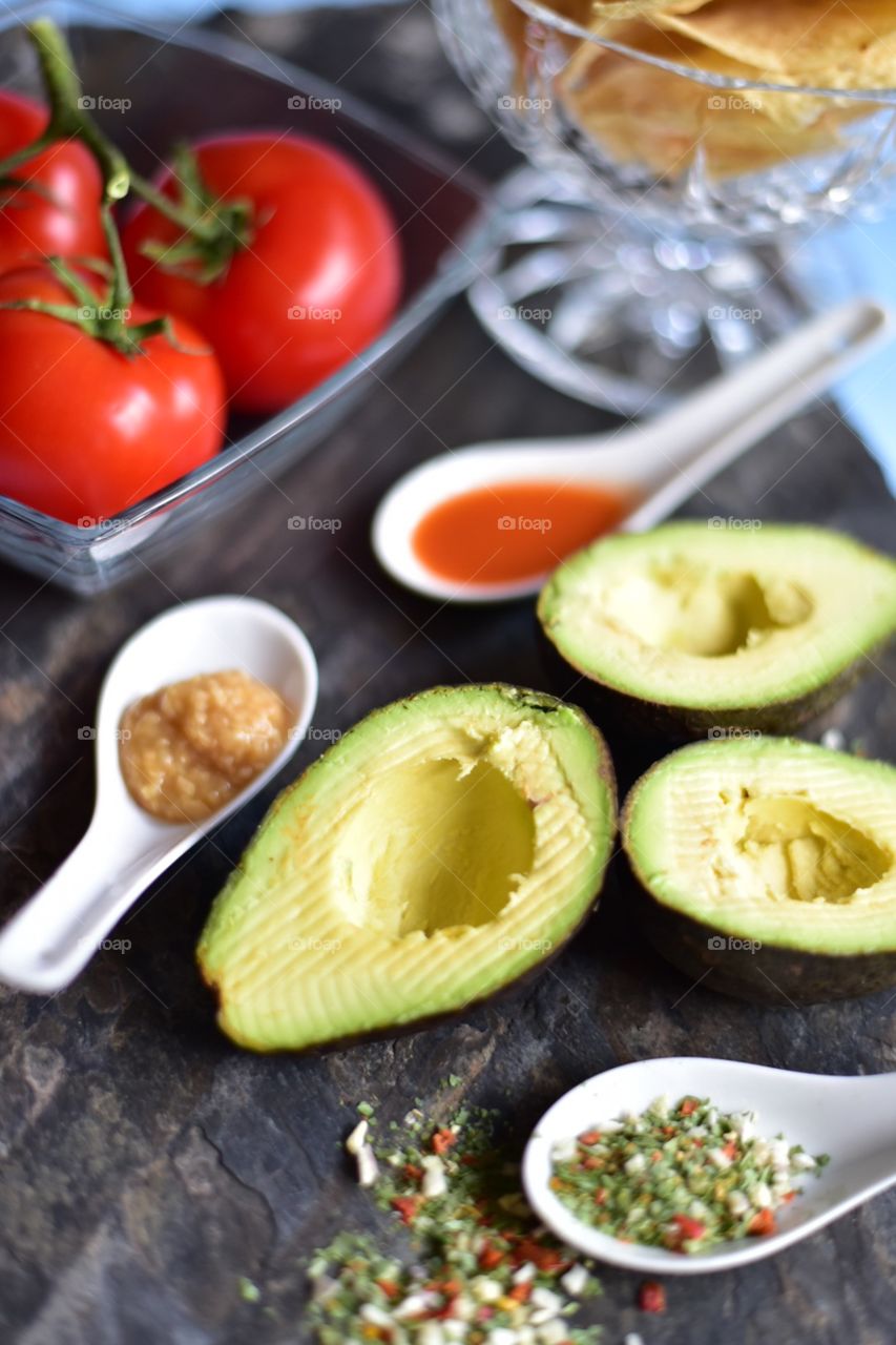 Healthy vegetables for spring time cooking at home. Tomatoes, avocado and spices for the perfect guacamole.