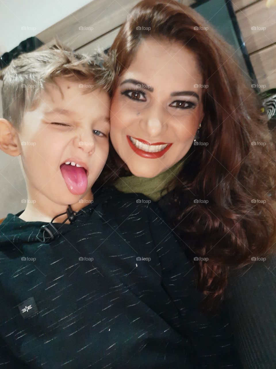 smiling mother and son sticking out their tongues.