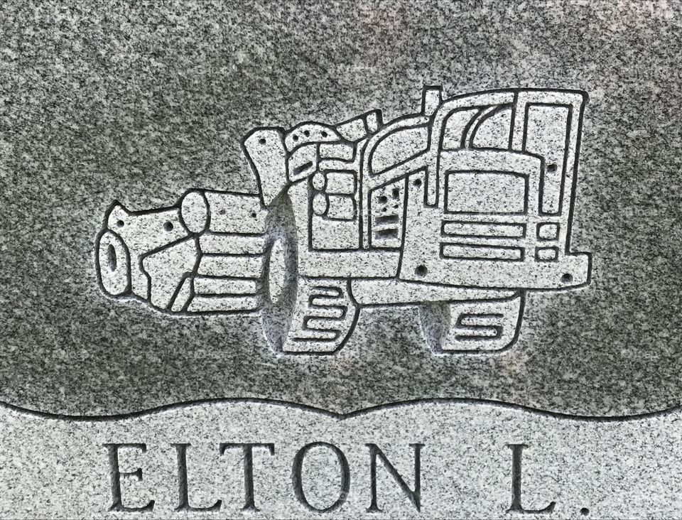 An engraving on a tombstone of a heavy construction road equipment. 