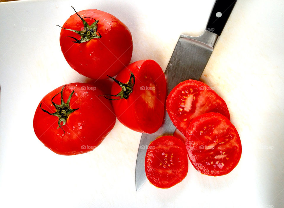 Tomatoes with knife on cutting board