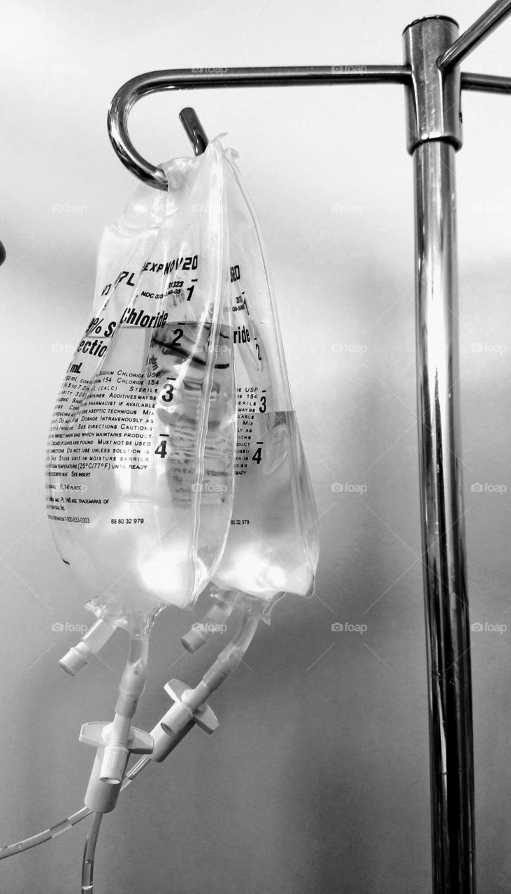 A double dose of saline bags hanging on a pole.