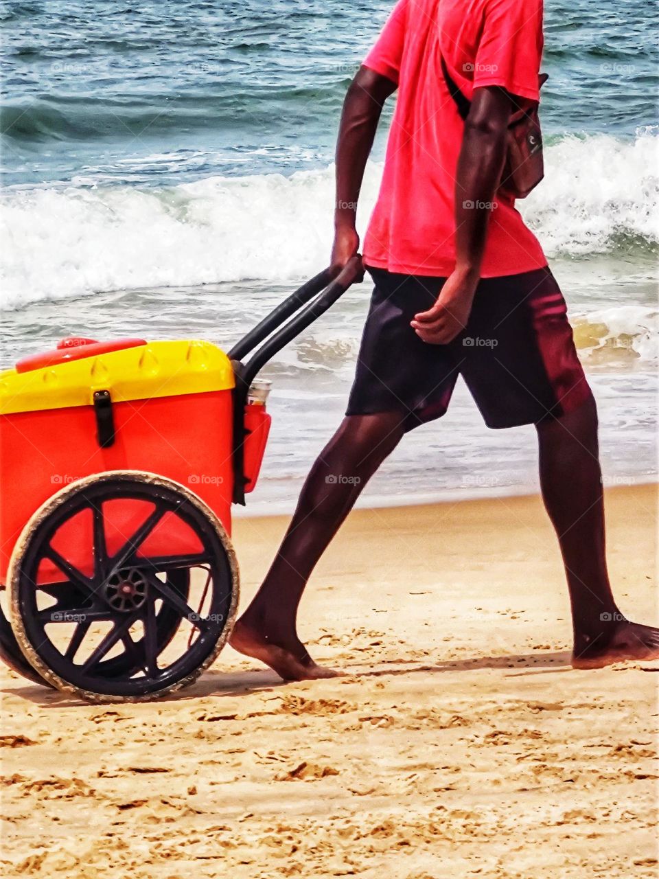 On the beach I watch the popsicle seller pulling his colorful cart with its rubber wheels, two  circles.