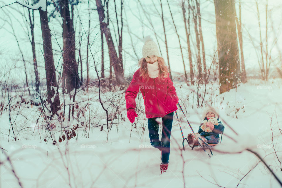 Teenage girl enjoying snow with her little sister enjoying wintertime