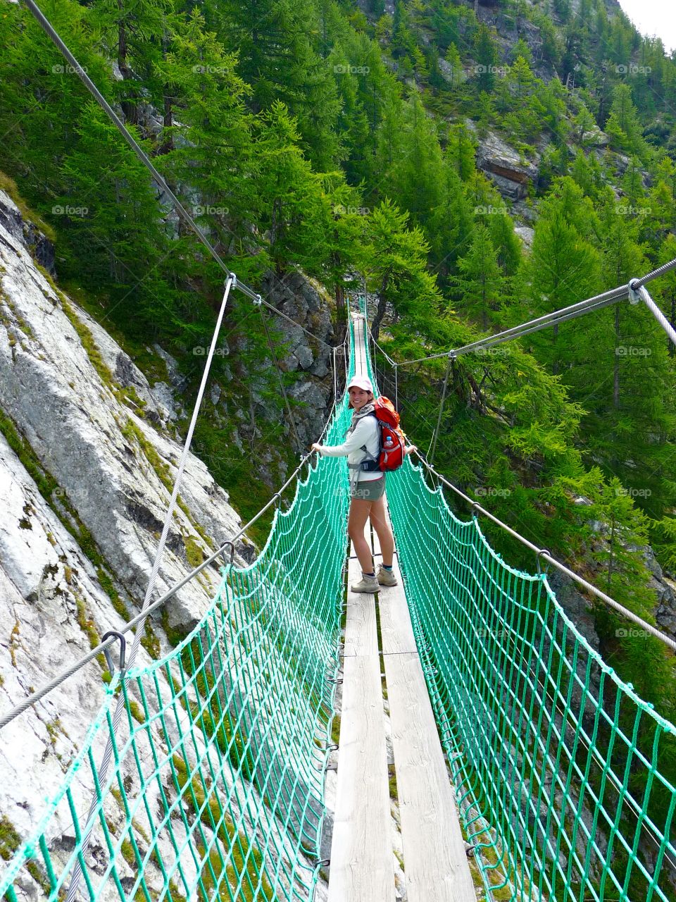 Woman on a rope bridge. Balancing on a rope bridge during a hiking tour in the Swiss Alps
