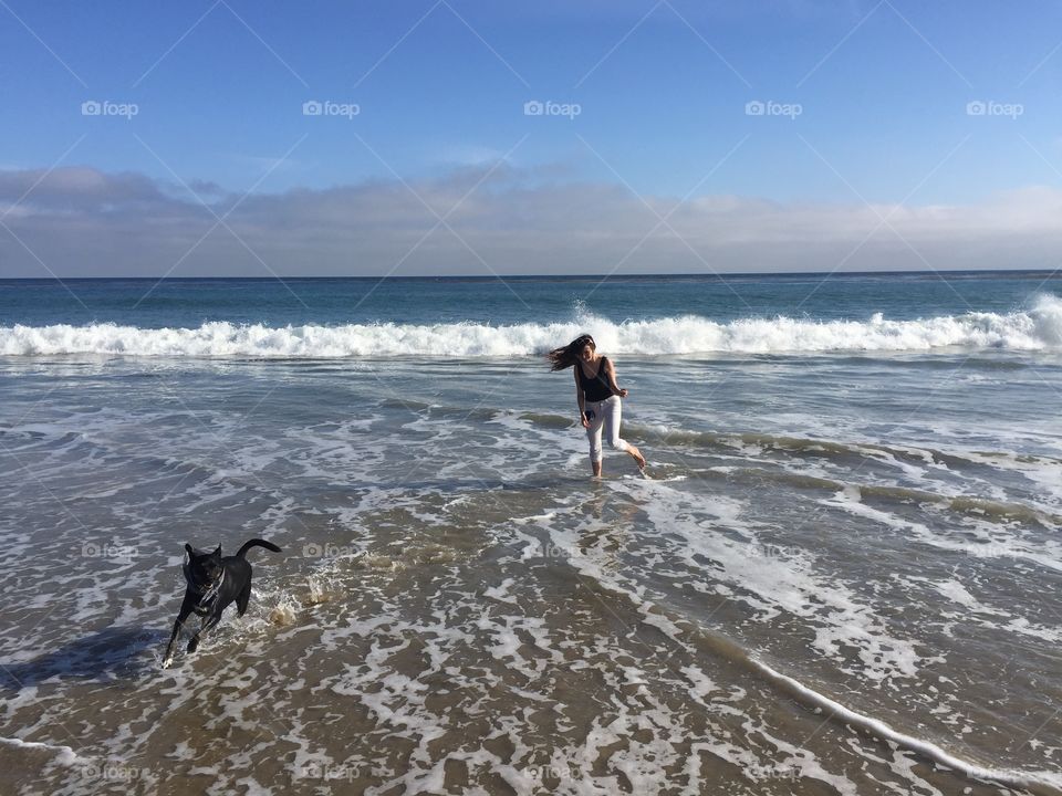 Teenage girl playing with dog in sea