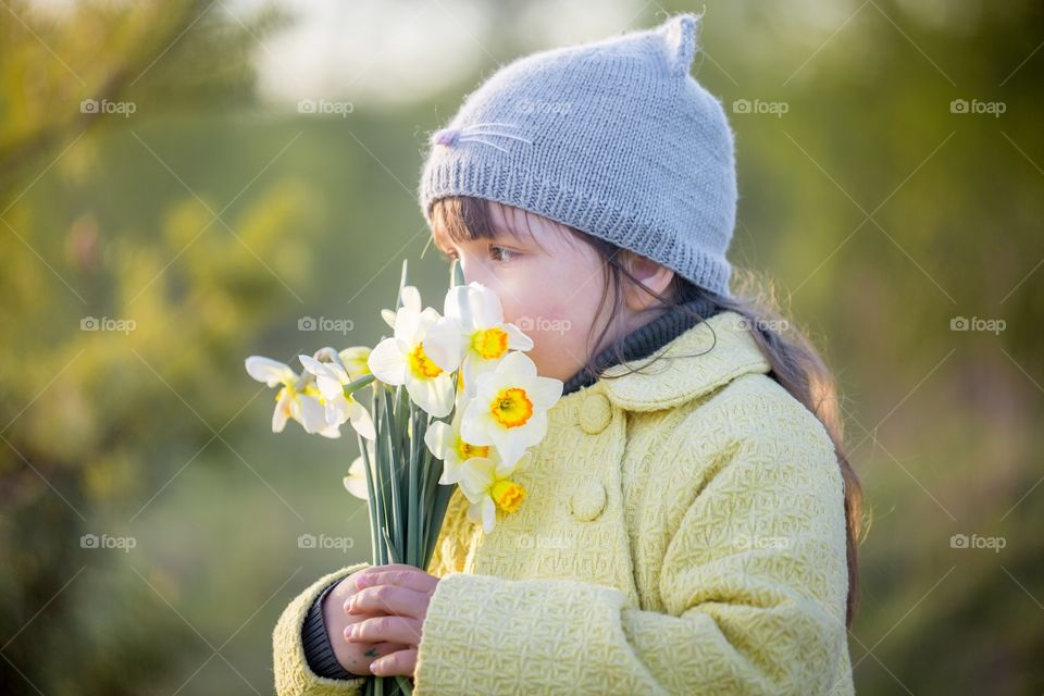 Little girl with narcissus bouquet in spring park.