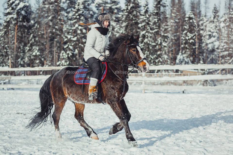 Teenage girl horseback jumping at cold winter day