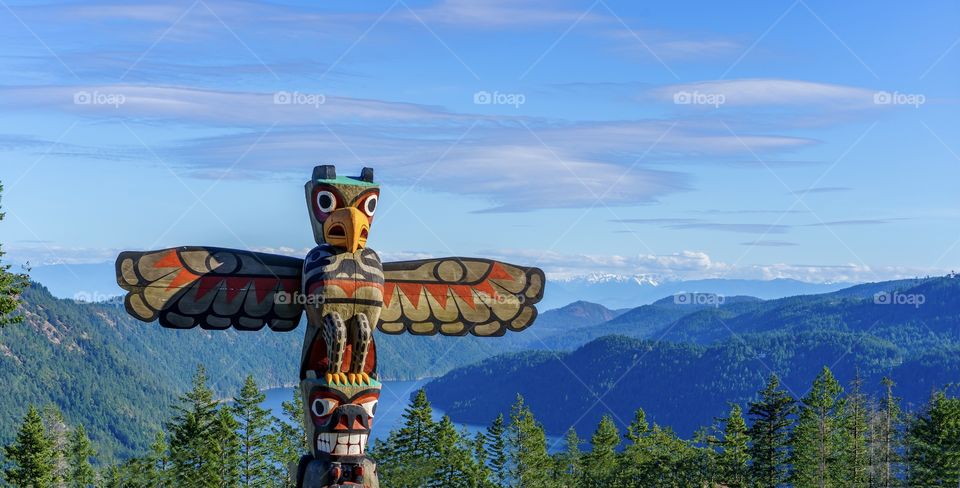 Totem pole overlooking mountain and ocean scenery